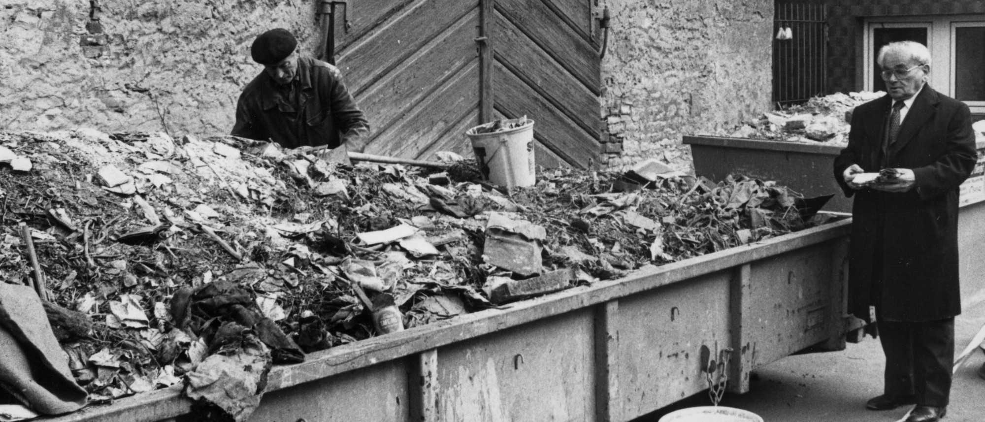 Schuttcontainer, vor dem zwei Personen stehen